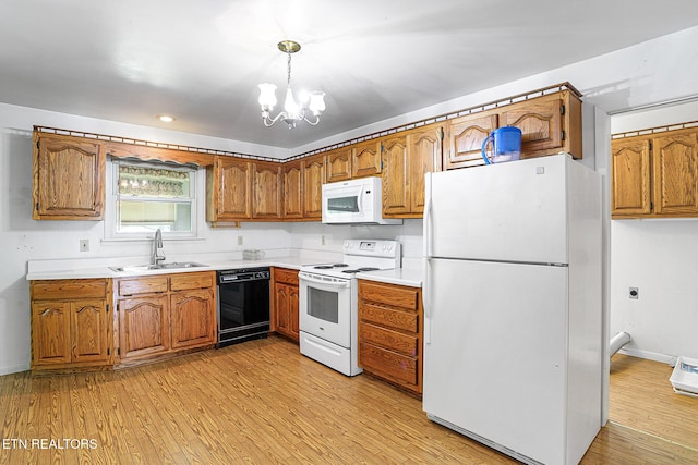 kitchen with white appliances, a sink, brown cabinetry, light wood-type flooring, and a chandelier