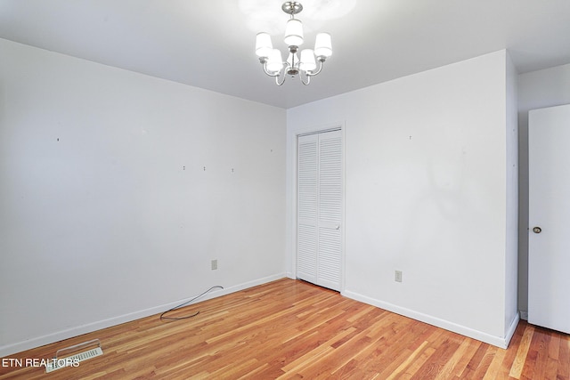 spare room with light wood-style flooring, baseboards, and a chandelier