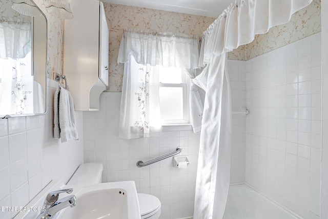 full bathroom with a sink, tile walls, toilet, and tiled shower