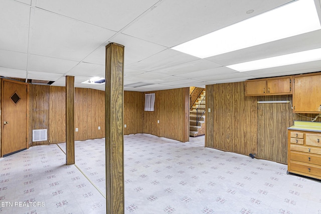 finished below grade area with stairway, wooden walls, and a drop ceiling