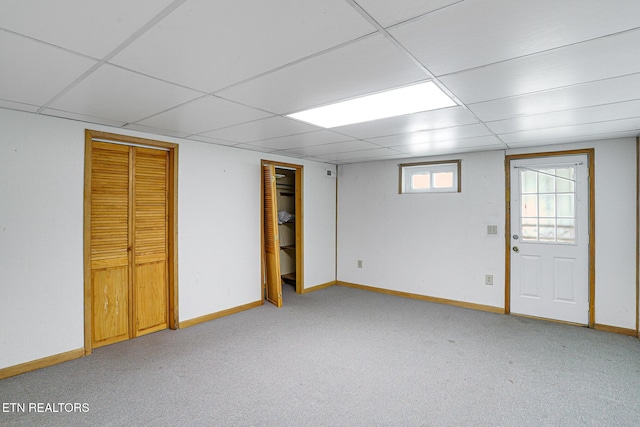 below grade area featuring a paneled ceiling, light colored carpet, and baseboards