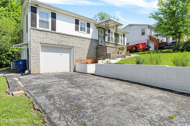 view of front of home featuring stone siding, a garage, and driveway