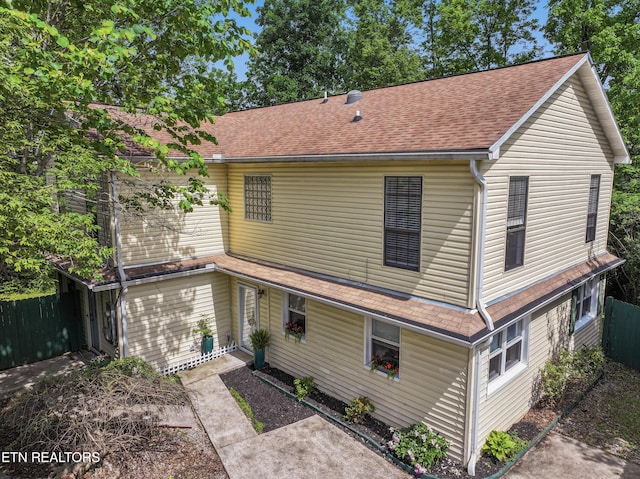 back of house featuring a shingled roof and fence