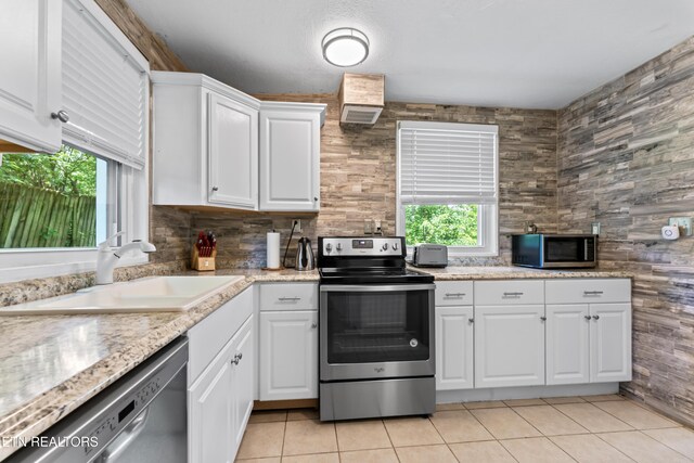 kitchen featuring appliances with stainless steel finishes, a sink, plenty of natural light, and white cabinetry