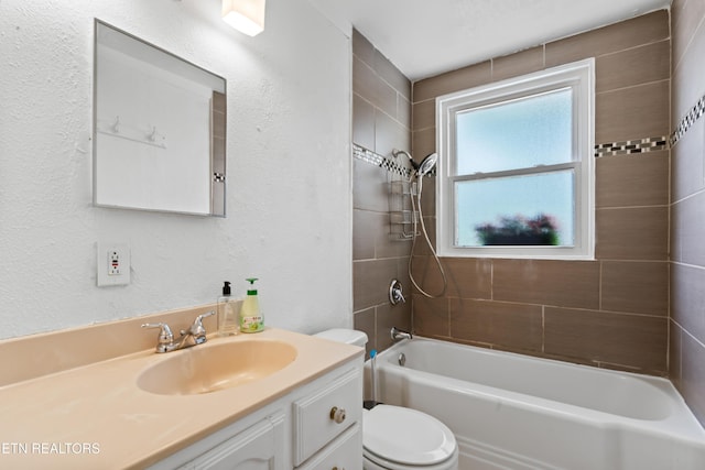 bathroom with toilet, vanity, washtub / shower combination, and a textured wall