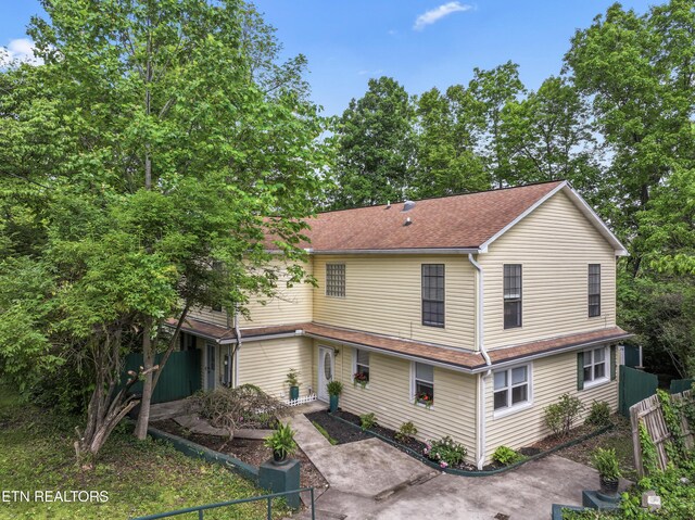 view of front of house featuring fence, a patio area, roof with shingles, and central AC unit