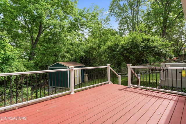 wooden deck featuring a storage shed, an outdoor structure, and fence