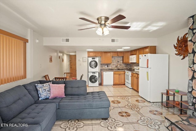 living area with stacked washing machine and dryer, a ceiling fan, and light tile patterned floors