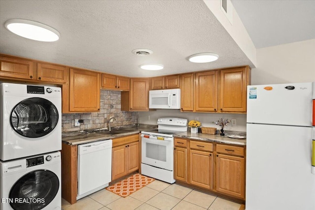 kitchen with white appliances, stacked washer / drying machine, a sink, light tile patterned flooring, and decorative backsplash