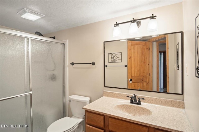 bathroom featuring a shower stall, toilet, vanity, and a textured ceiling