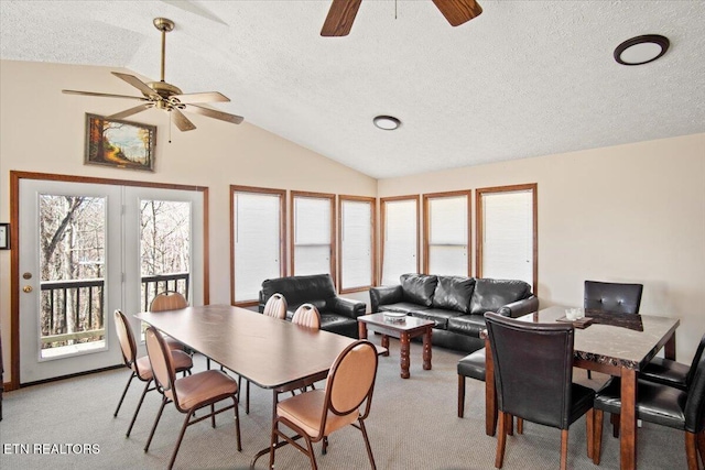 dining room with a ceiling fan, a textured ceiling, vaulted ceiling, light colored carpet, and healthy amount of natural light