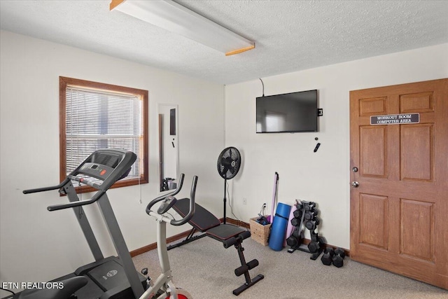 workout area featuring carpet floors, a textured ceiling, and baseboards