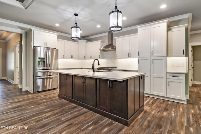 kitchen featuring stainless steel refrigerator with ice dispenser, wall chimney exhaust hood, a sink, light countertops, and dark wood finished floors
