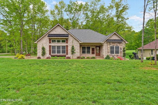 view of front of home featuring a front lawn, brick siding, and roof with shingles