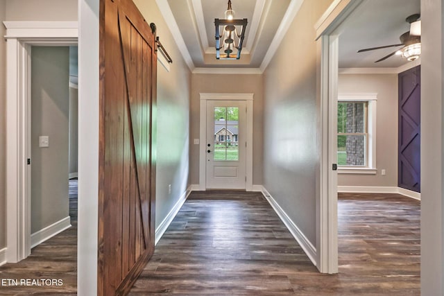 doorway to outside with a barn door, crown molding, dark wood-type flooring, baseboards, and ceiling fan