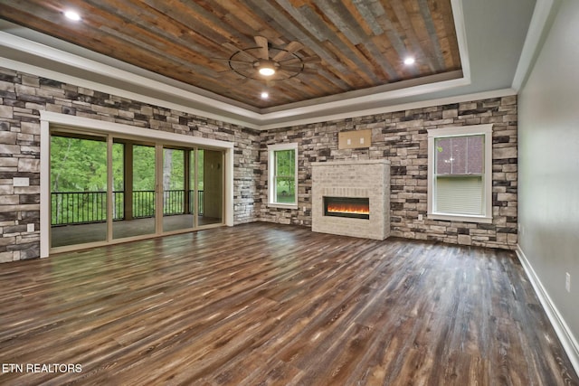 unfurnished living room with a tray ceiling, a glass covered fireplace, wooden ceiling, wood finished floors, and a ceiling fan