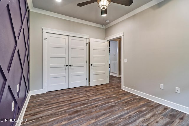unfurnished bedroom with dark wood-style flooring, baseboards, a closet, crown molding, and a ceiling fan