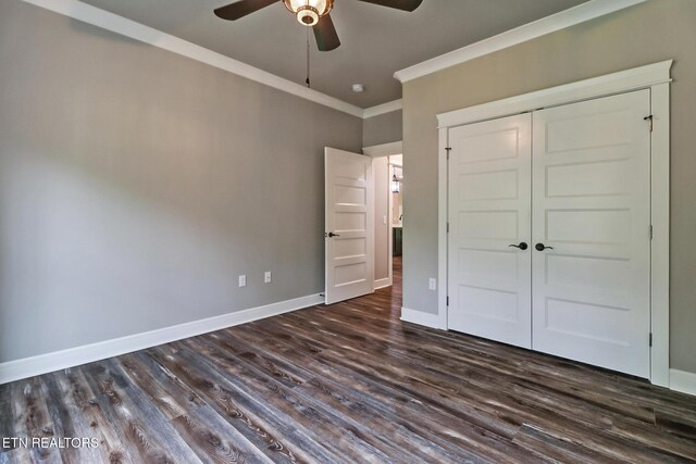 unfurnished bedroom with ornamental molding, dark wood-style floors, baseboards, a closet, and a ceiling fan