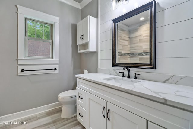 bathroom featuring wood finished floors, baseboards, toilet, and vanity