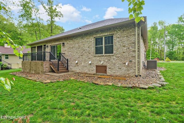 rear view of house with brick siding, a yard, cooling unit, and stairway