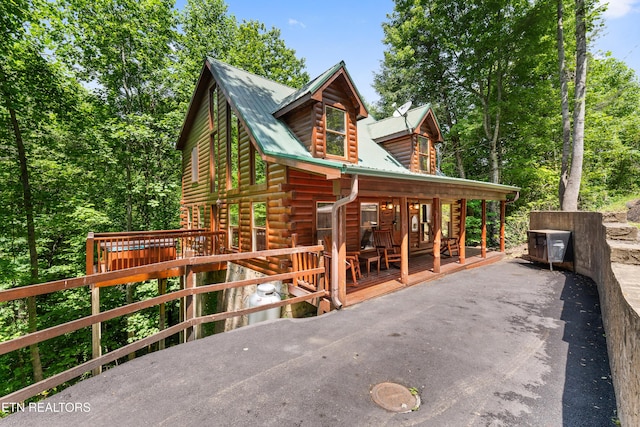 view of home's exterior featuring metal roof, covered porch, and log siding