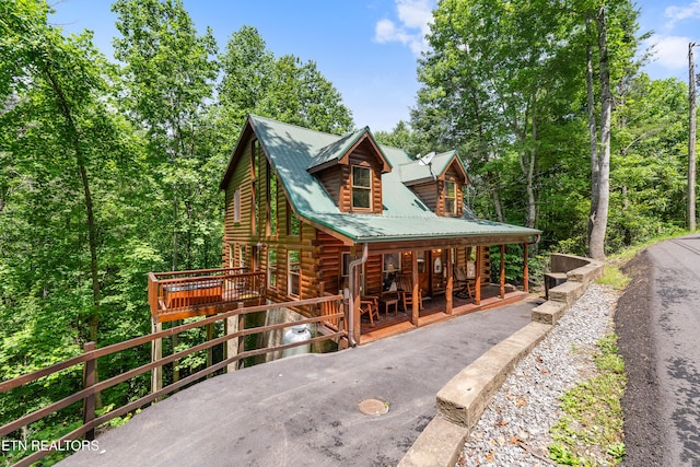 view of front of house featuring log exterior, a porch, and metal roof