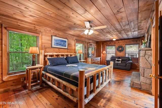 bedroom featuring wooden ceiling, hardwood / wood-style flooring, and wood walls