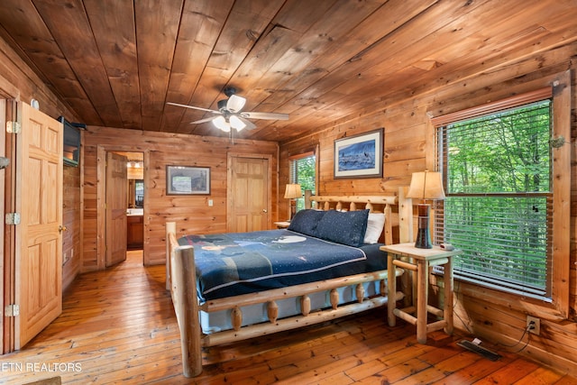 bedroom with light wood-style flooring, wooden walls, multiple windows, and wood ceiling