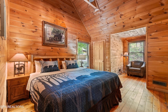 bedroom with light wood-type flooring, wooden walls, vaulted ceiling, and access to exterior