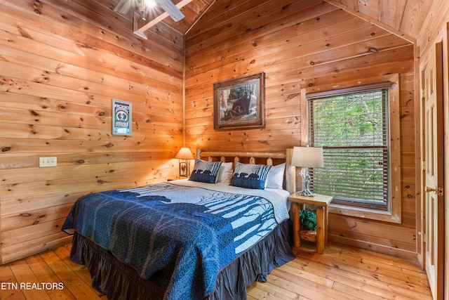 bedroom with wooden walls, hardwood / wood-style floors, and vaulted ceiling