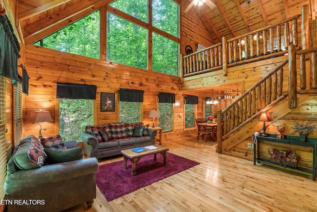 living room featuring wood walls, high vaulted ceiling, healthy amount of natural light, stairway, and wooden ceiling