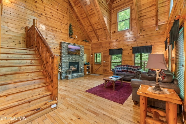 living room featuring high vaulted ceiling, wood ceiling, wood walls, a stone fireplace, and hardwood / wood-style flooring