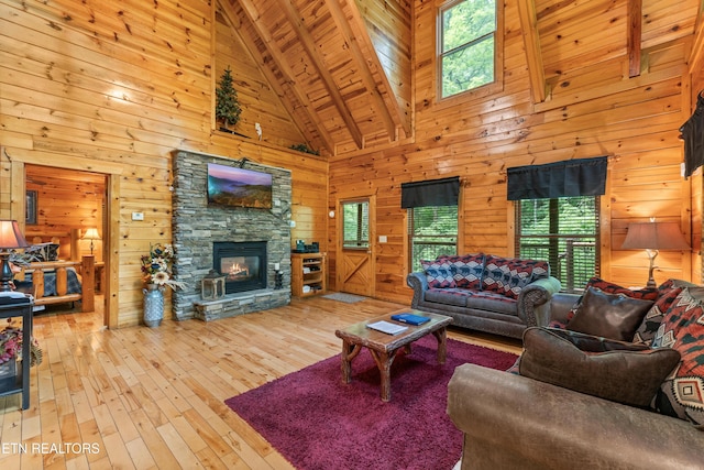 living room featuring high vaulted ceiling, wood walls, beam ceiling, hardwood / wood-style flooring, and a stone fireplace