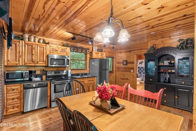 dining space featuring a chandelier, light wood-style flooring, wooden ceiling, and wood walls