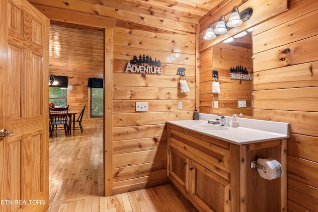 bathroom featuring wooden walls, wood-type flooring, and vanity