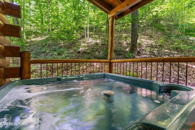wooden terrace featuring a hot tub and a wooded view
