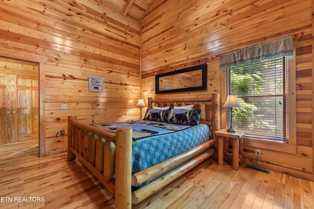 bedroom featuring wooden walls and light wood-style flooring