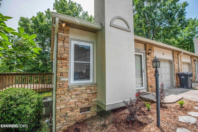 view of home's exterior featuring stone siding, concrete driveway, an attached garage, and fence