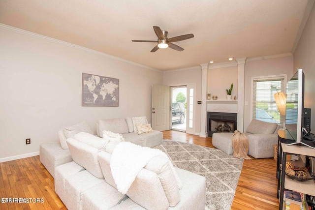 living room featuring light wood-type flooring, a ceiling fan, plenty of natural light, and crown molding