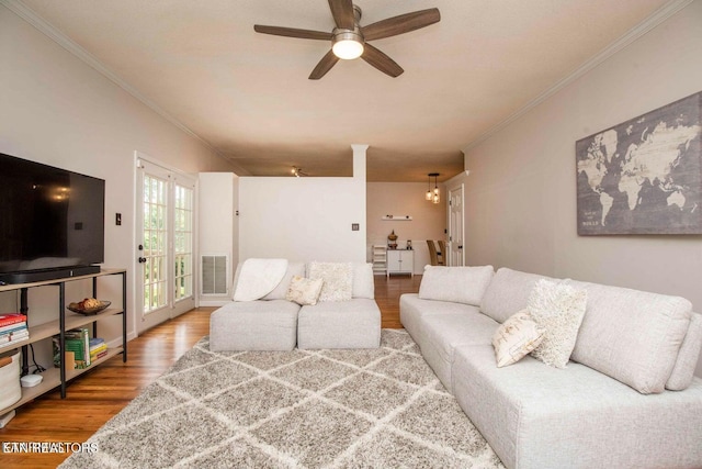 living area with crown molding, wood finished floors, and ceiling fan