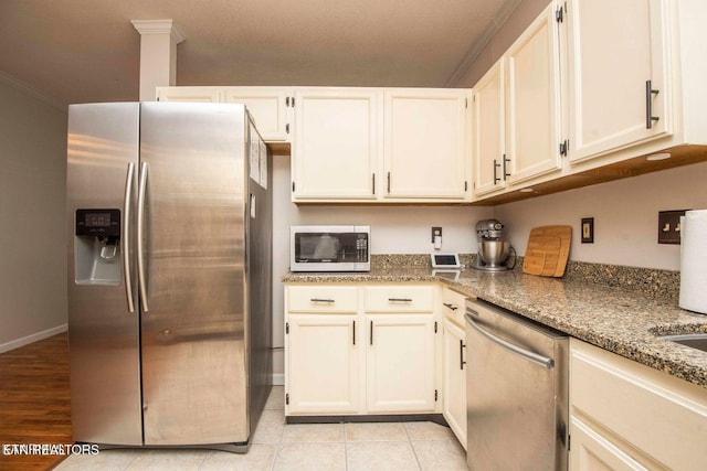 kitchen featuring appliances with stainless steel finishes, light stone countertops, white cabinets, ornamental molding, and light tile patterned floors