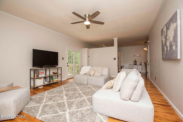 living area with ornamental molding, a ceiling fan, wood finished floors, and baseboards