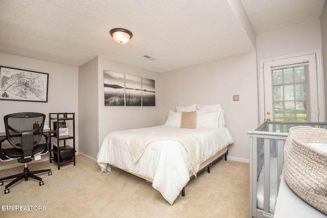 bedroom featuring light colored carpet, baseboards, a textured ceiling, and a desk