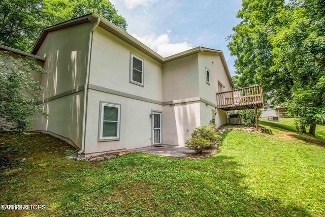 back of house featuring stucco siding, a yard, and a wooden deck