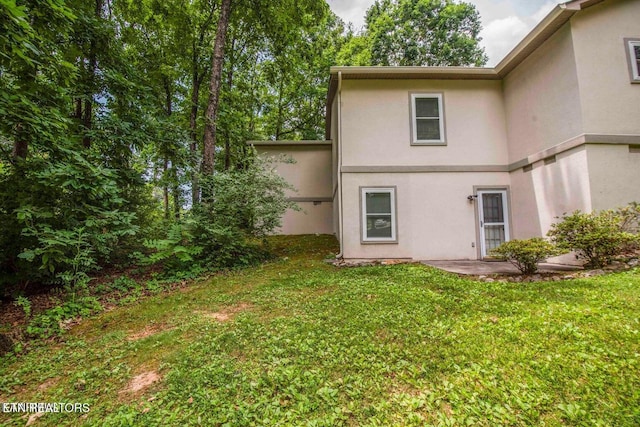 rear view of property with stucco siding and a yard