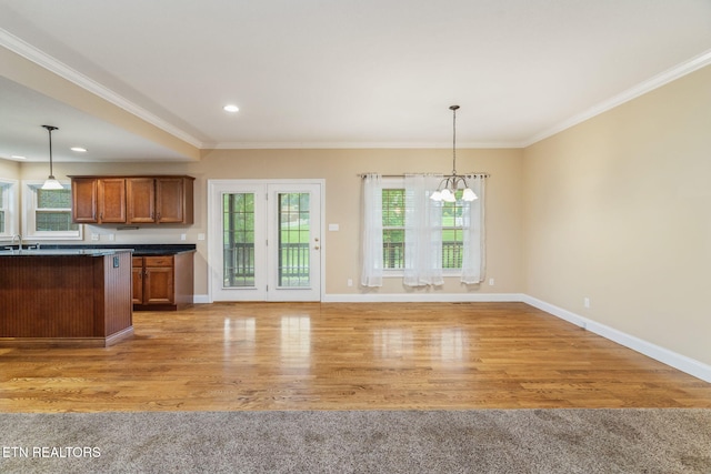 kitchen with dark countertops, brown cabinets, decorative light fixtures, baseboards, and crown molding