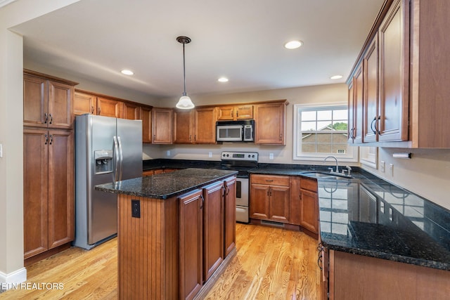 kitchen featuring appliances with stainless steel finishes, a sink, light wood-type flooring, dark stone countertops, and recessed lighting