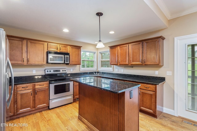 kitchen with appliances with stainless steel finishes, a sink, crown molding, light wood-style floors, and brown cabinetry