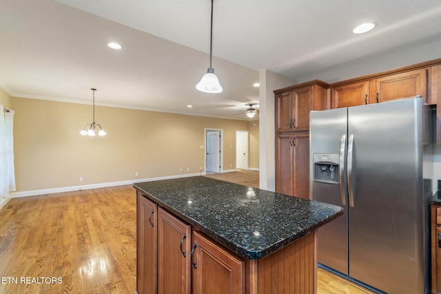 kitchen featuring stainless steel fridge, brown cabinets, ornamental molding, pendant lighting, and baseboards