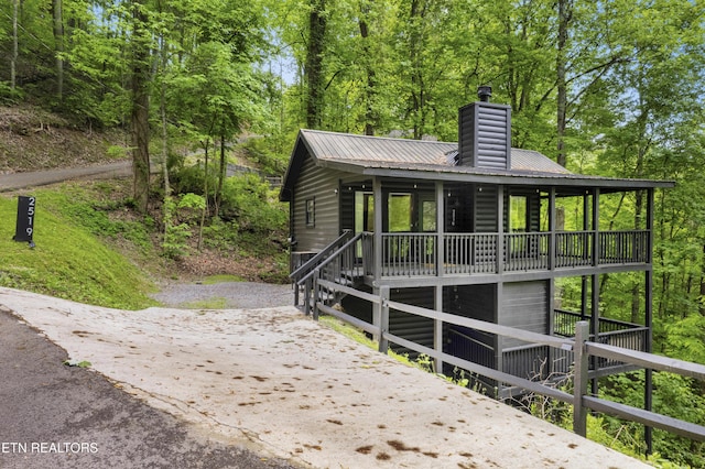 view of front of property with a chimney, metal roof, and driveway